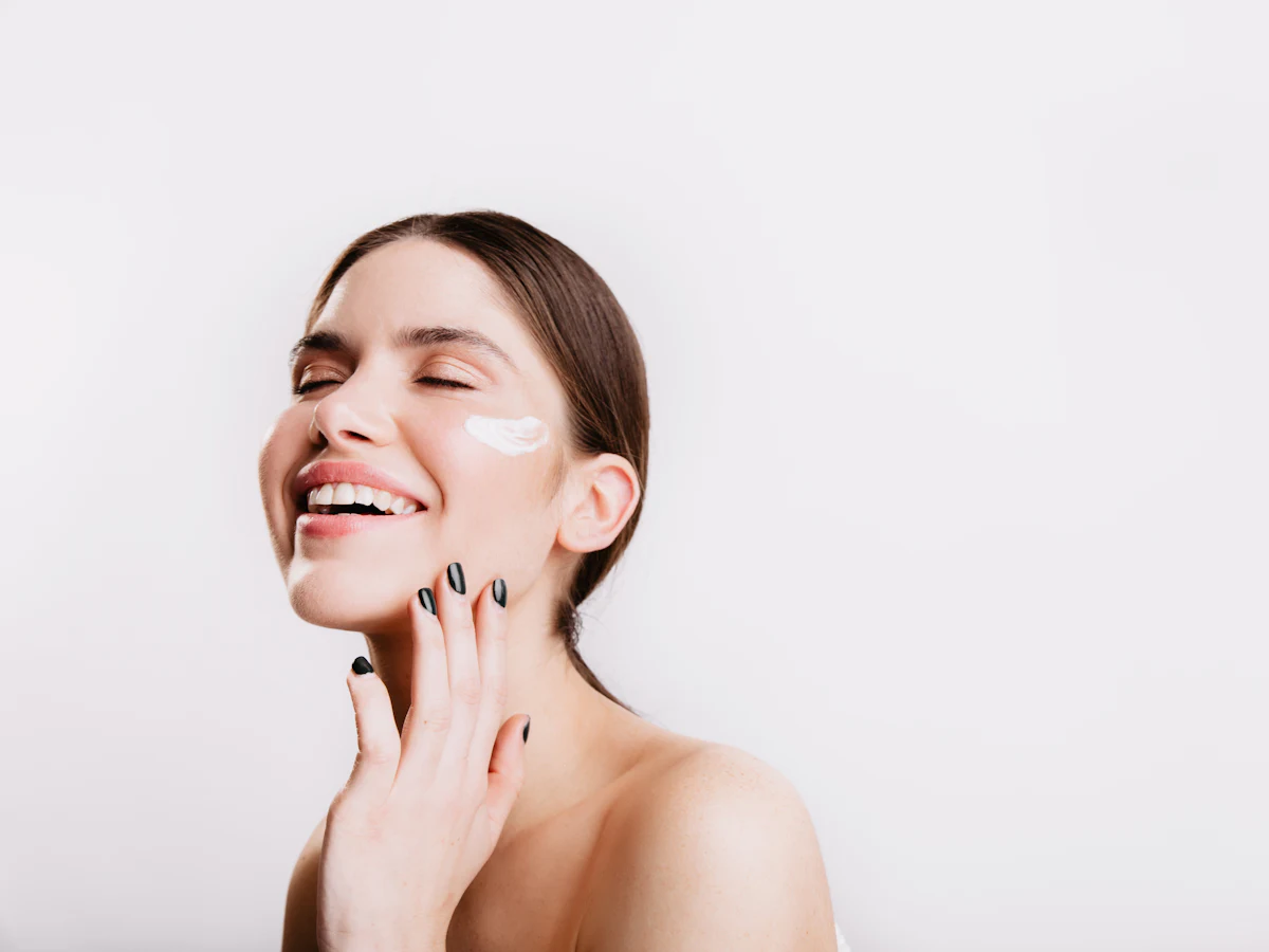 Smiling woman touching her cheek after applying moisturiser