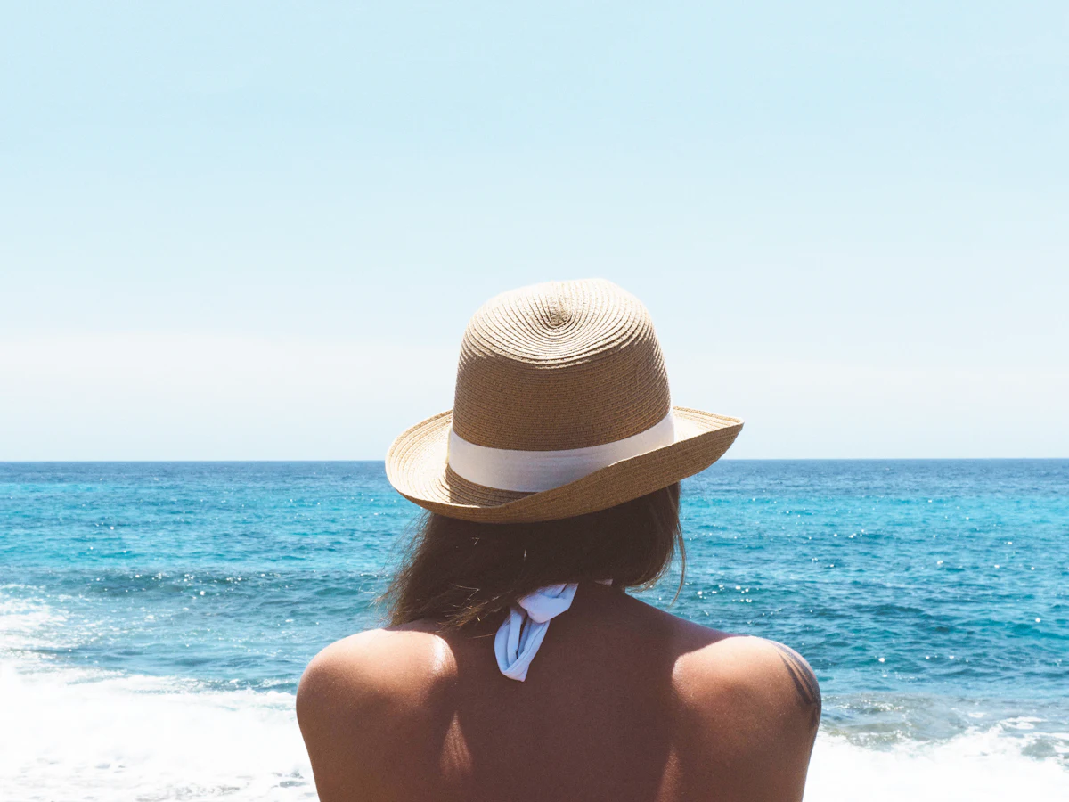 Woman in a sun hat looking out over the sea