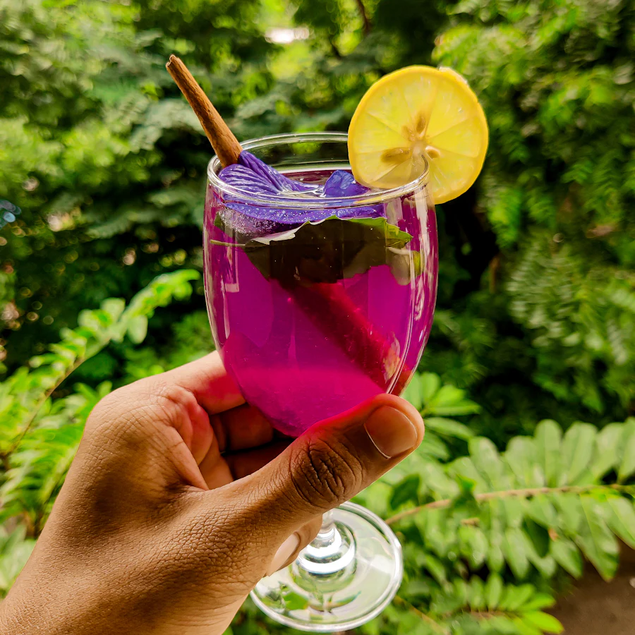 A glass of butterfly pea tea turning purple with lemon