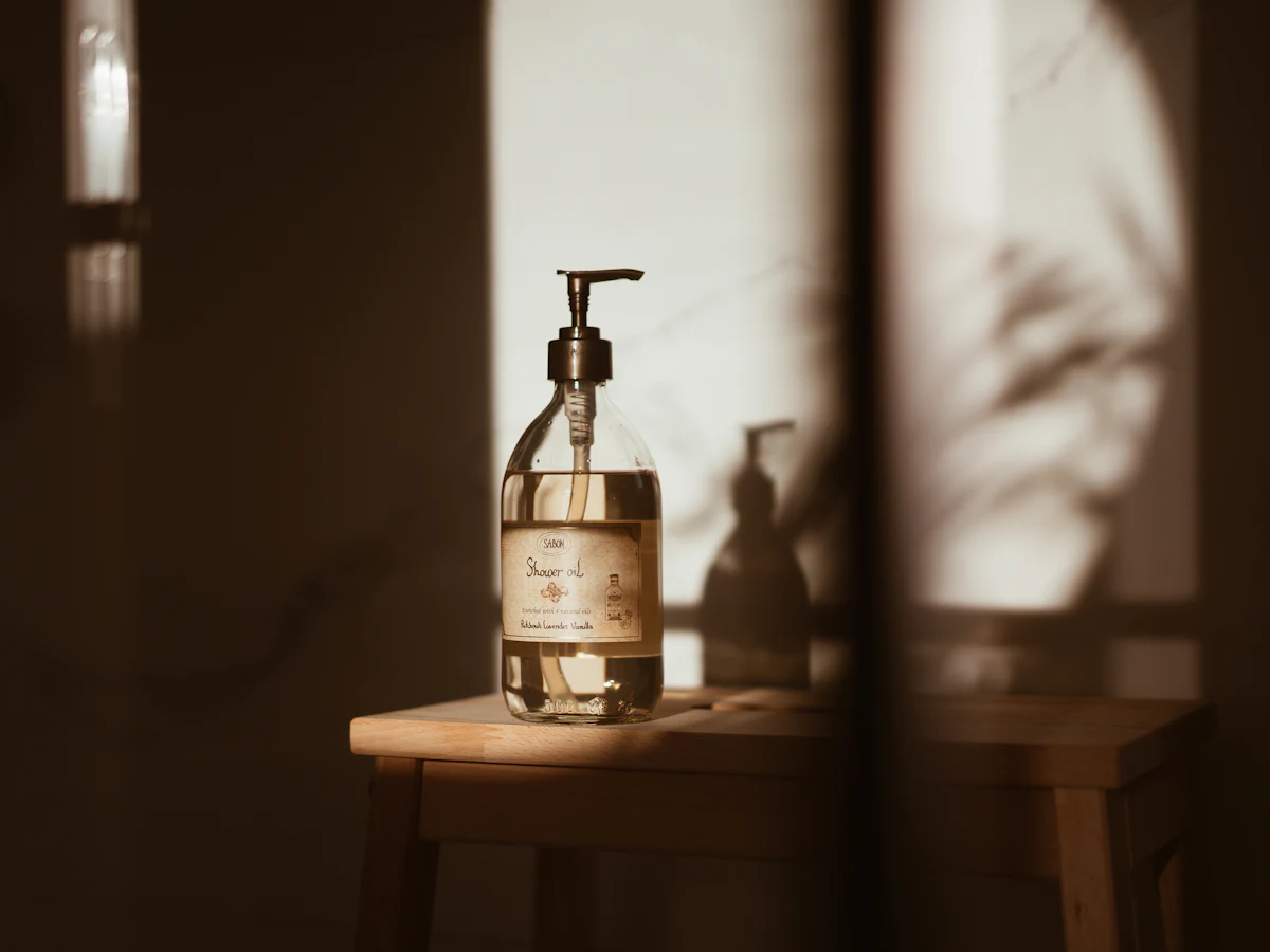 A glass pump bottle of body wash in warm light