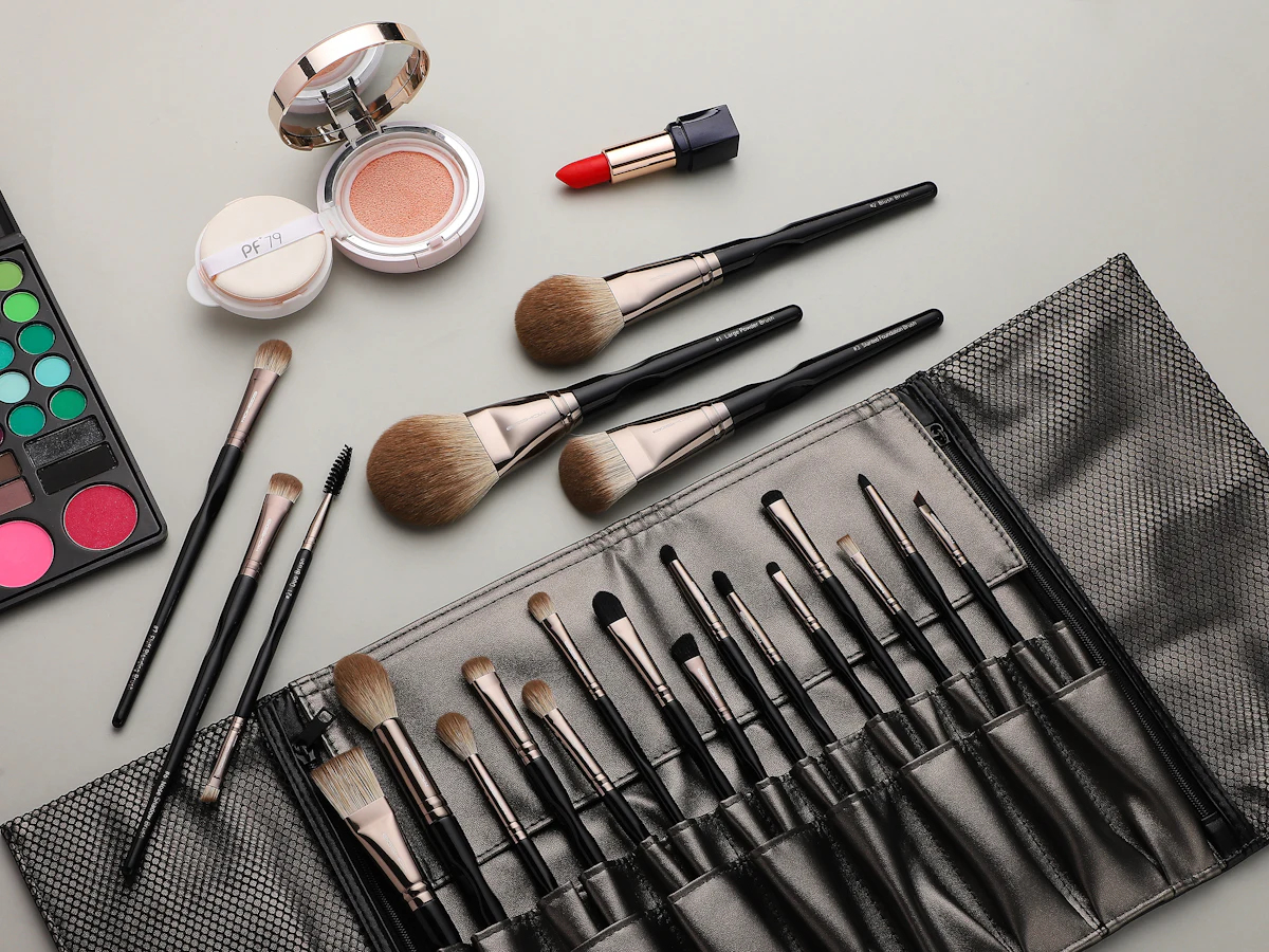 Makeup brushes in a roll beside a compact and palette
