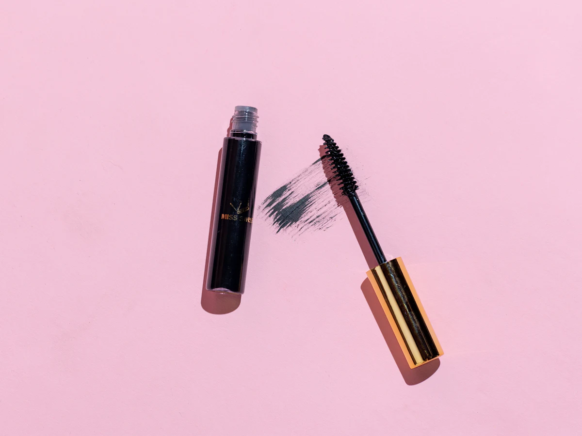 A mascara wand on a pink background