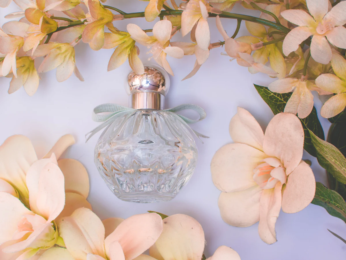 A glass perfume bottle among pale flowers